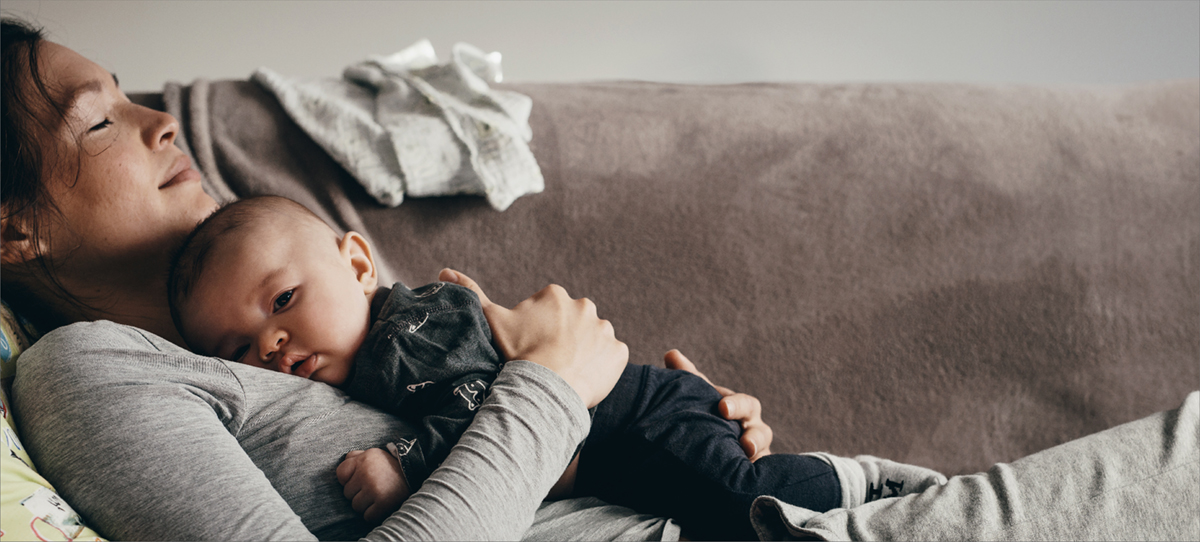 Woman with baby resting on couch.