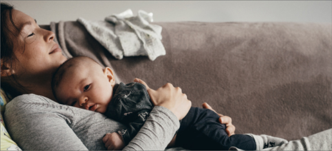 Woman with baby resting on couch.